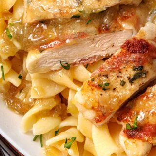 Golden chicken breast on dinner plate with pasta.