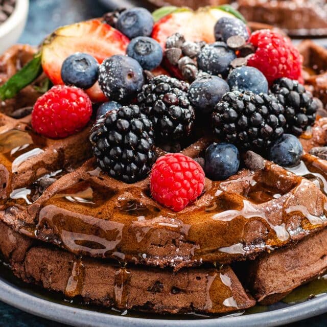 Plate of waffles, topped with syrup and fruit.