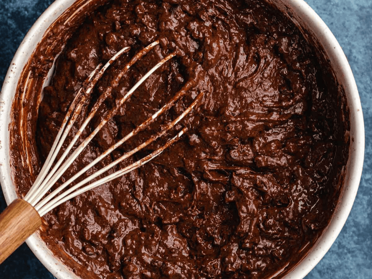 Chocolate batter in bowl with whisk.