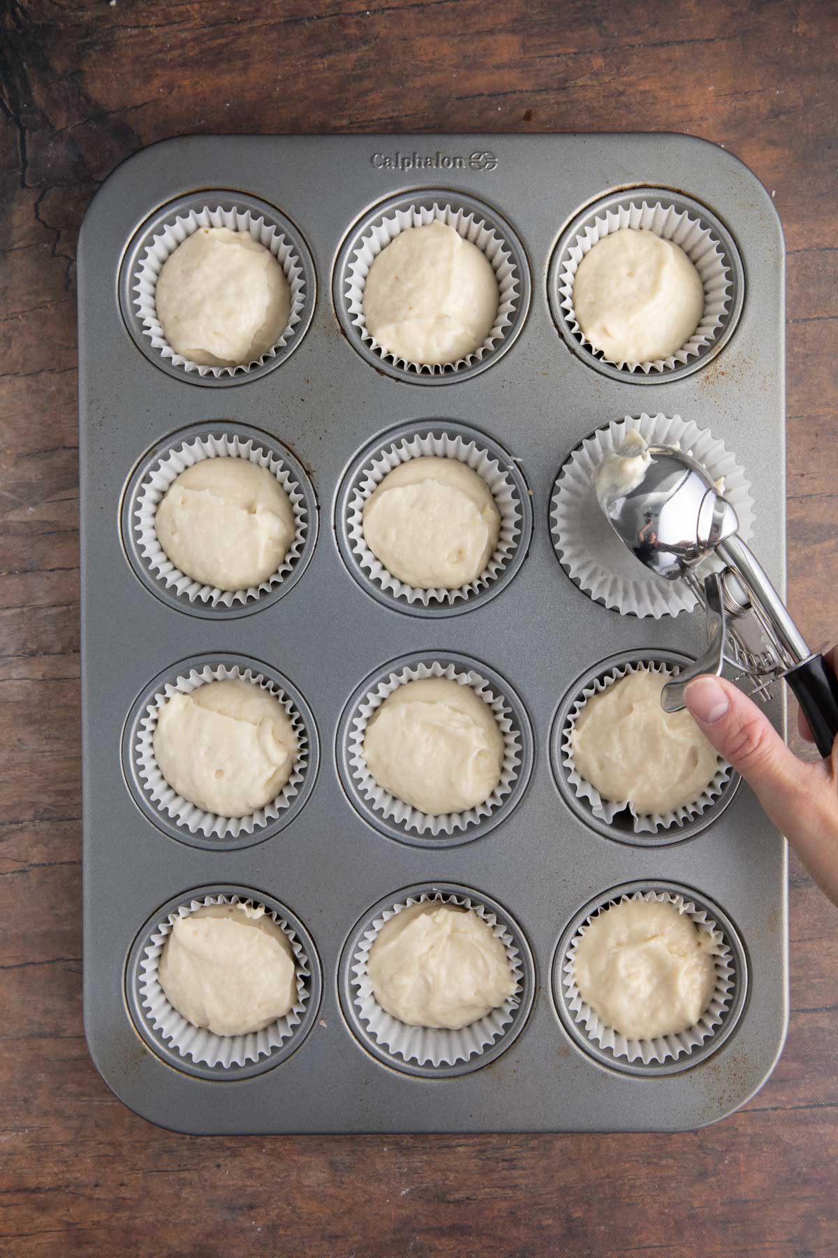Coconut Cupcakes scooping batter with ice cream scoop into muffin tin