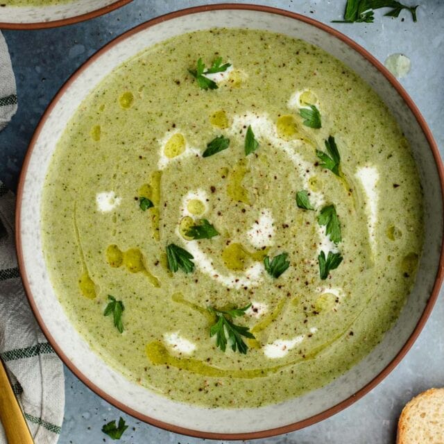 Creamy broccoli soup in bowl with garnish.