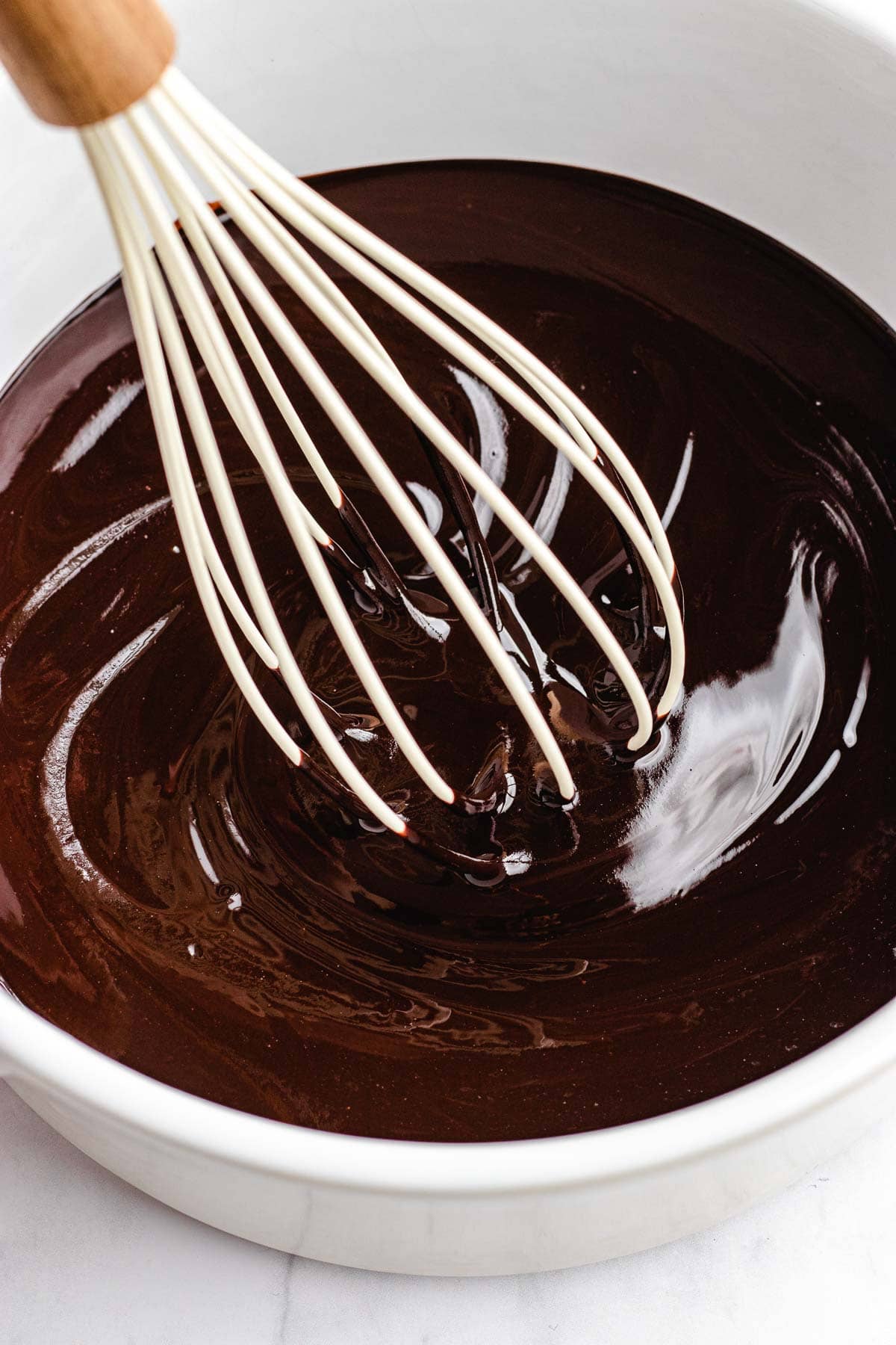 Dark Chocolate Frosting whisking melted butter and chocolate in glass mixing bowl