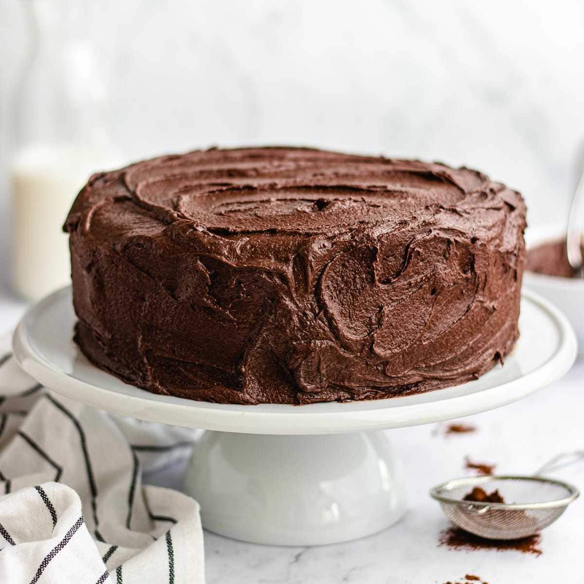 Dark Chocolate Frosting frosted layer cake on white cake stand