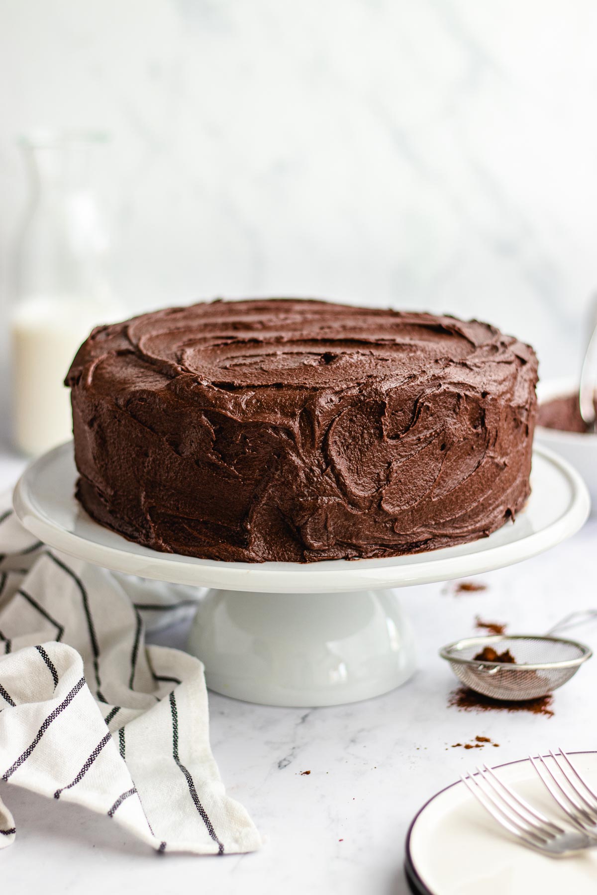 Dark Chocolate Frosting frosted layer cake on white cake stand