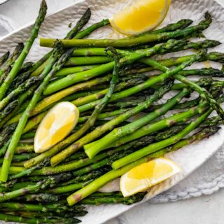 Garlic Lemon Asparagus on plate with lemon wedges