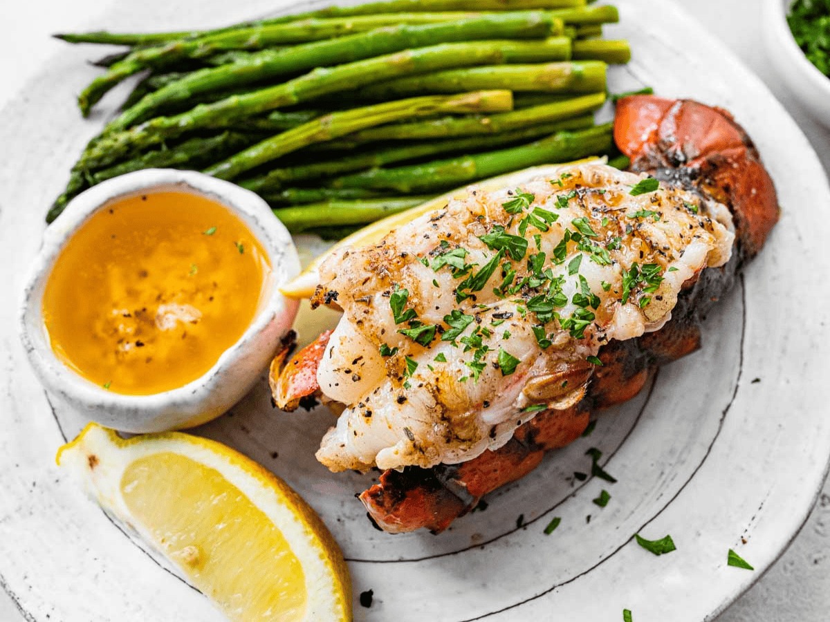 Grilled shellfish on dinner plate with butter and asparagus.