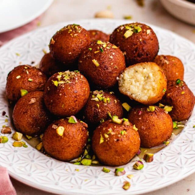 Round fried balls topped with syrup and pistachio.