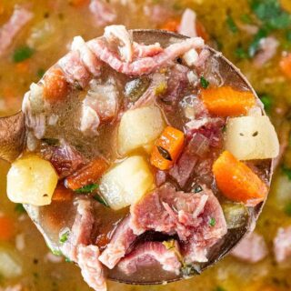 Hearty meat and vegetable soup in a ladle.