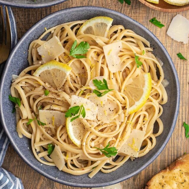 Dinner plate with pasta, lemon, and parmesan cheese.