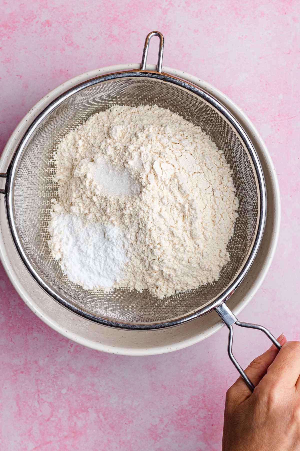 Pink Velvet Cake sifting dry ingredients into bowl