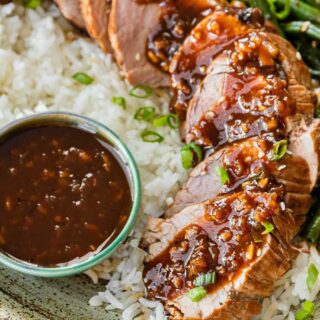 Pork loin on dinner plate with rice and sauce.