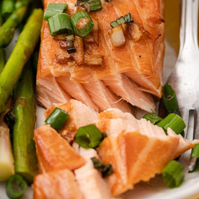 Salmon filet on dinner plate with asparagus, and fork.