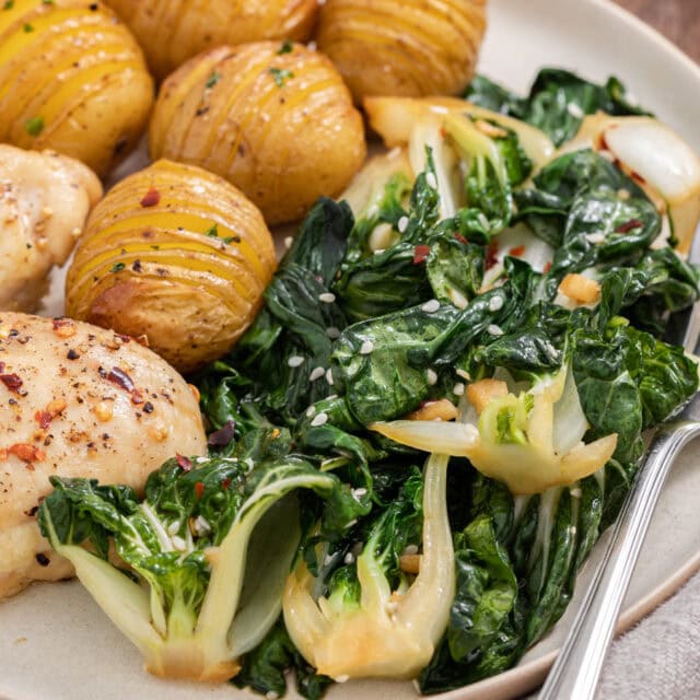 Bok choy on plate with potatoes and chicken.