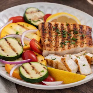 Grilled fish filet on dinner plate with vegetables.