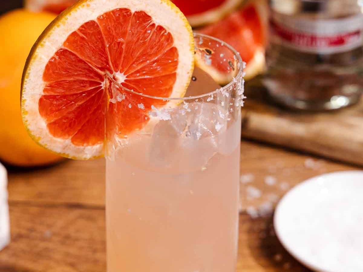 Cocktail in glass with salted rim and grapefruit wheel garnish.