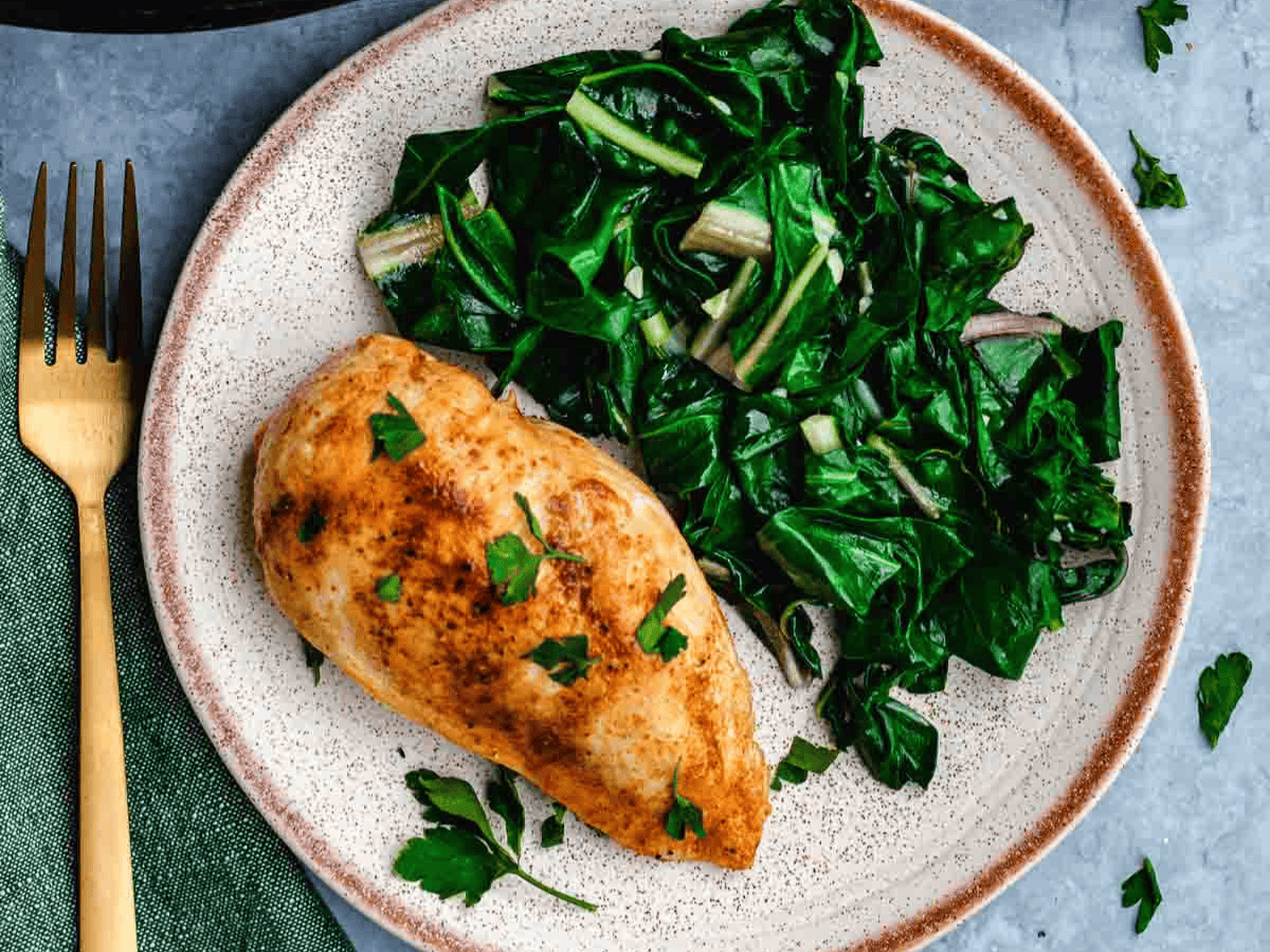 Dinner plate with leafy greens and chicken breast.
