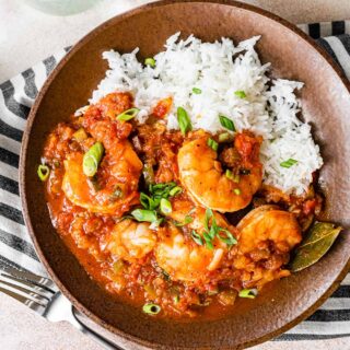 Shallow bowl with rice and saucy shrimp.