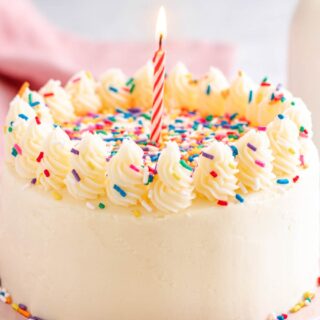 Frosted vanilla cake with rainbow sprinkles and one candle