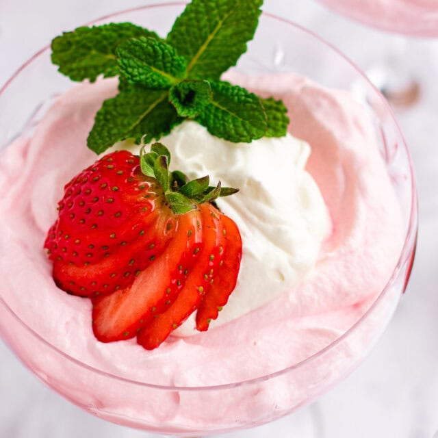 top down view of mousse garnished with berries, cream and mint