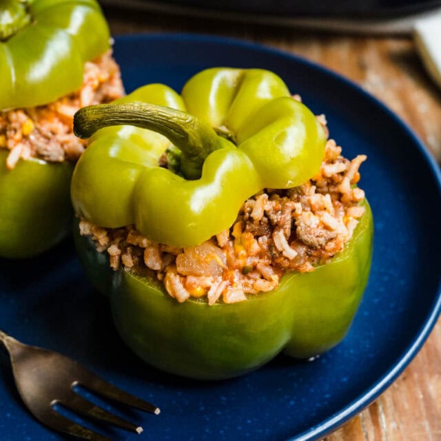 Filled bell peppers on dinner plate with fork.