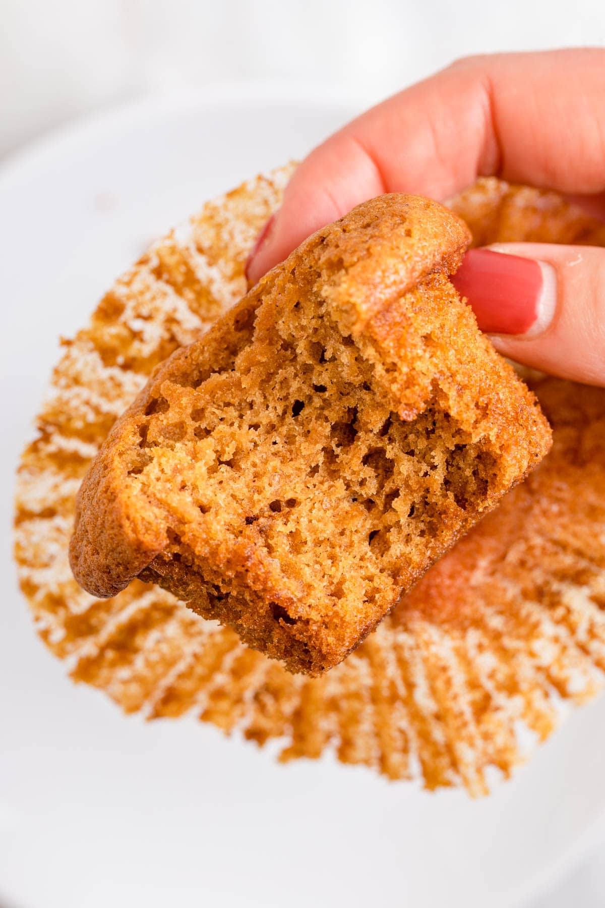 Sweet Potato Muffins holding unwrapped muffin with bite taken out of it