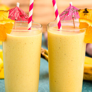 Two tropical smoothies with straws and umbrella garnishes.