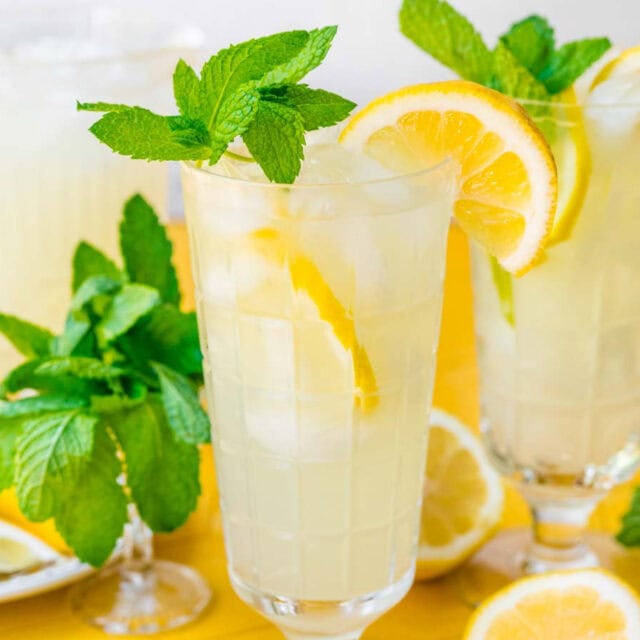 Two tall glasses of lemonade with lemon and mint leaves