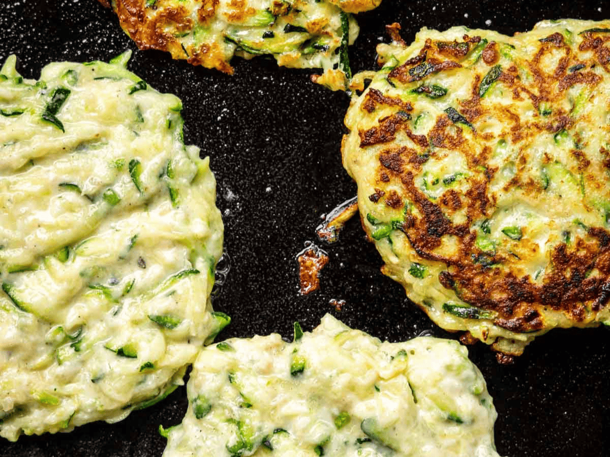Veggie fritters frying in pan.