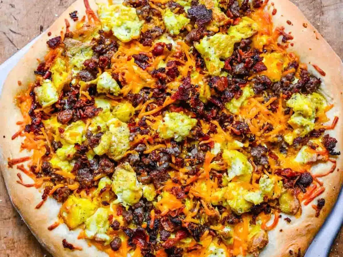 Baked pizza dough topped with eggs, sausage, bacon, and cheese.