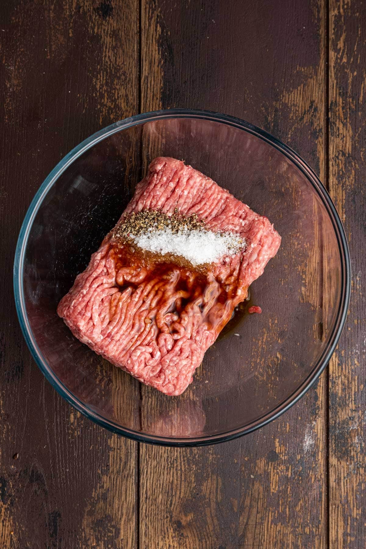Raw beef in mixing bowl with spices and ingredients 