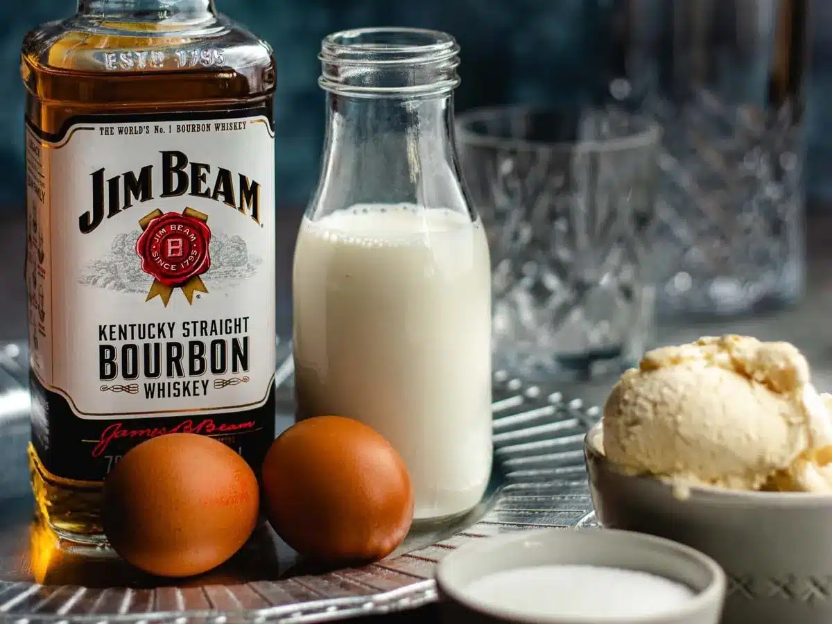 Bourbon, milk, eggs, and ice cream on countertop.