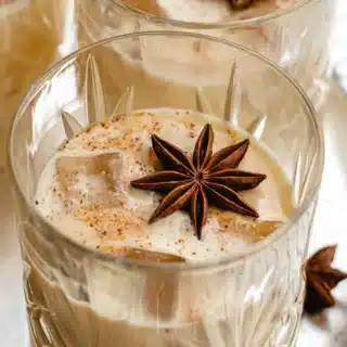 Cocktail in glass on ice with star anise garnish.