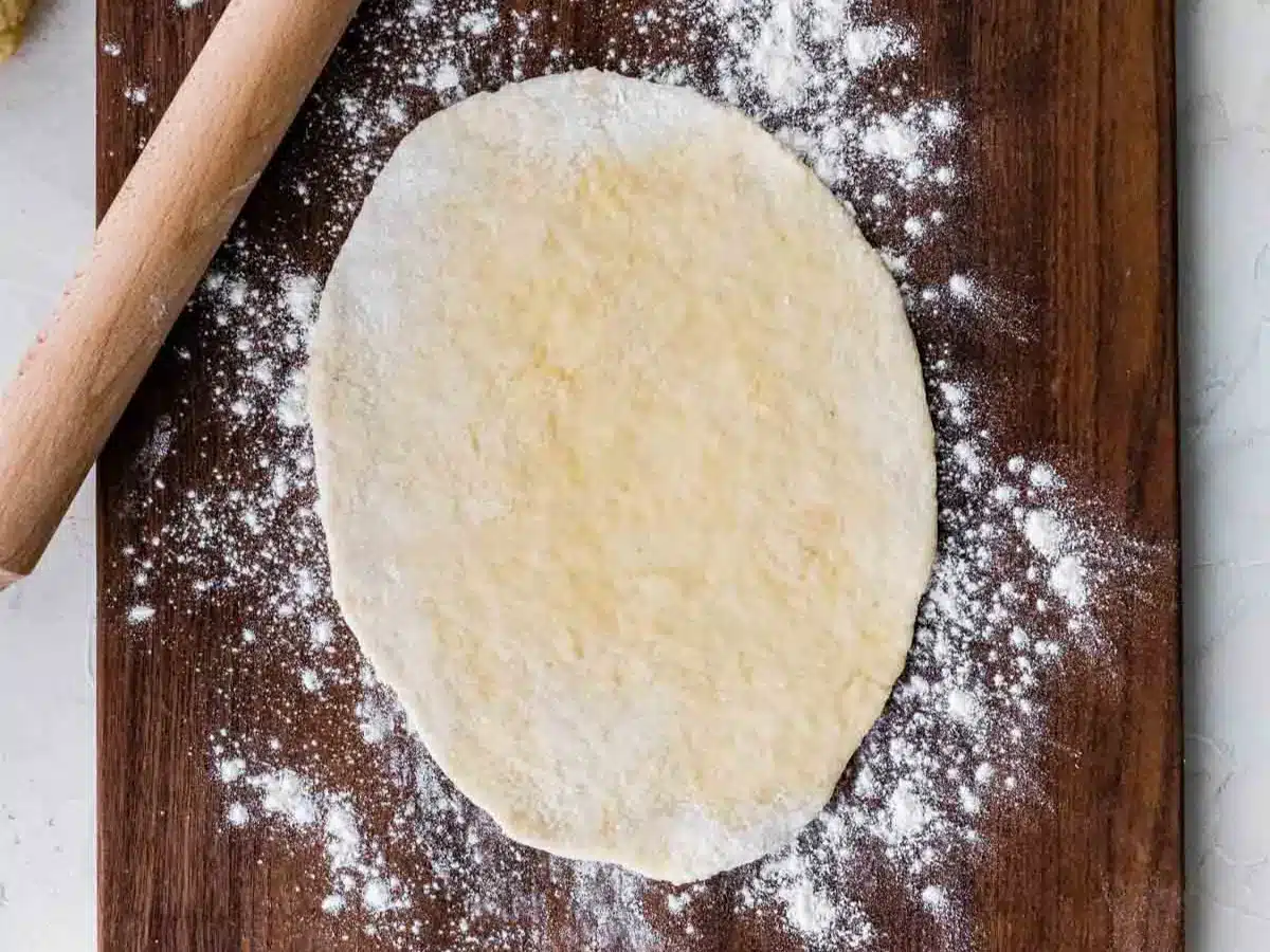 Bread dough rolled out on cutting board.