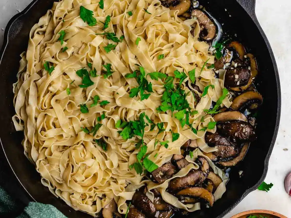 Pasta and criminis sautéing in pan.
