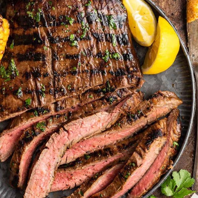 Sliced, grilled flank steak on serving plate.