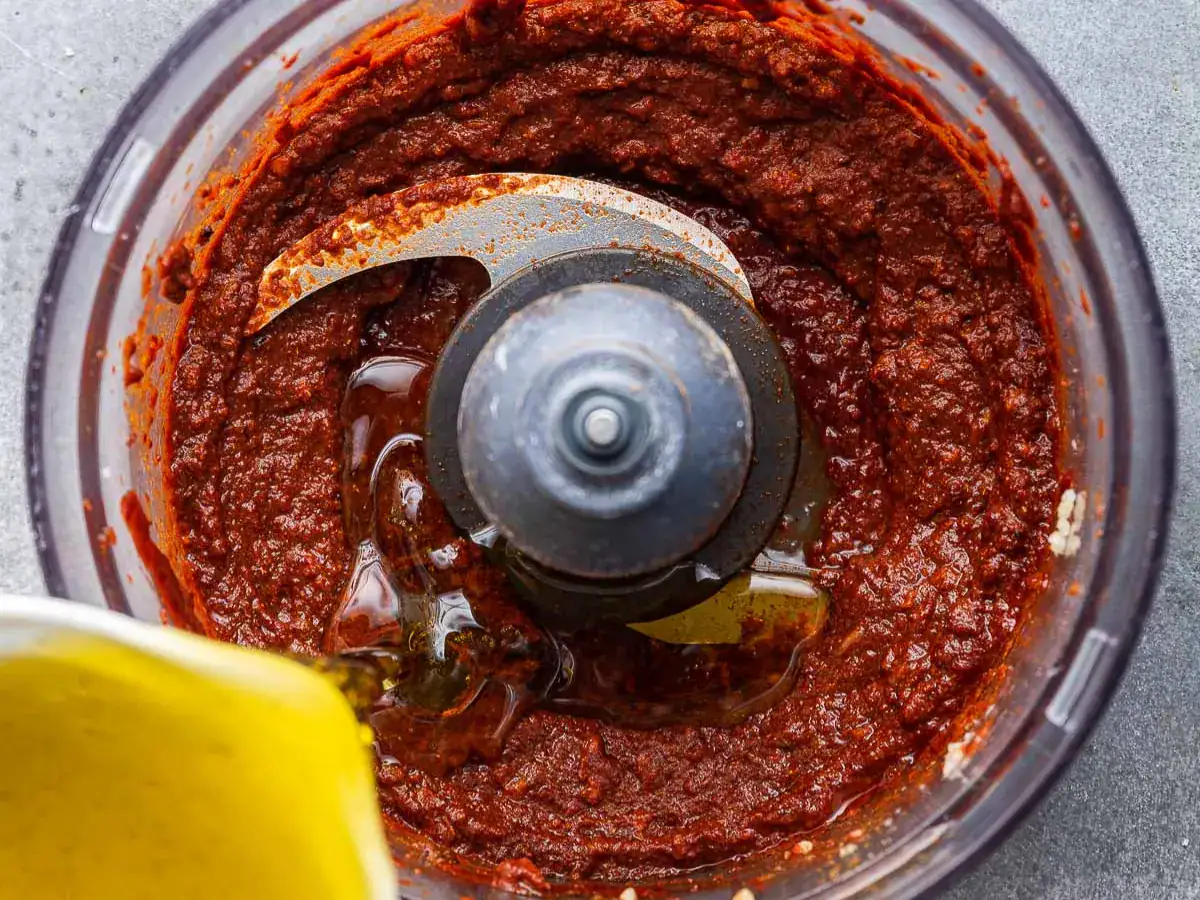 Oil added to spicy sauce in food processor.
