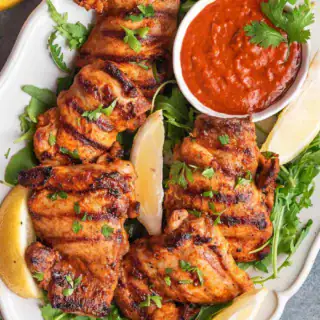 Grilled chicken thighs on serving plate.