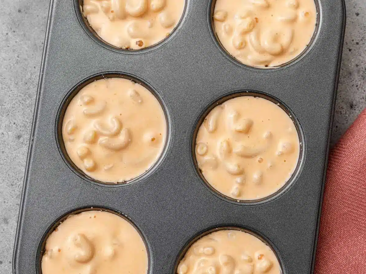 Pasta and cheese sauce portioned into muffin tin.