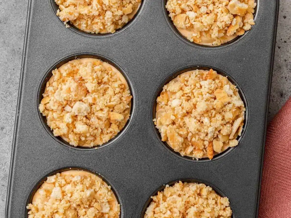 Crust of ritz crackers on top of savory appetizer in muffin tin.