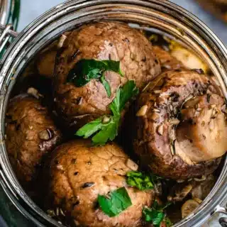 Jar of crimini mushrooms in vinegar.