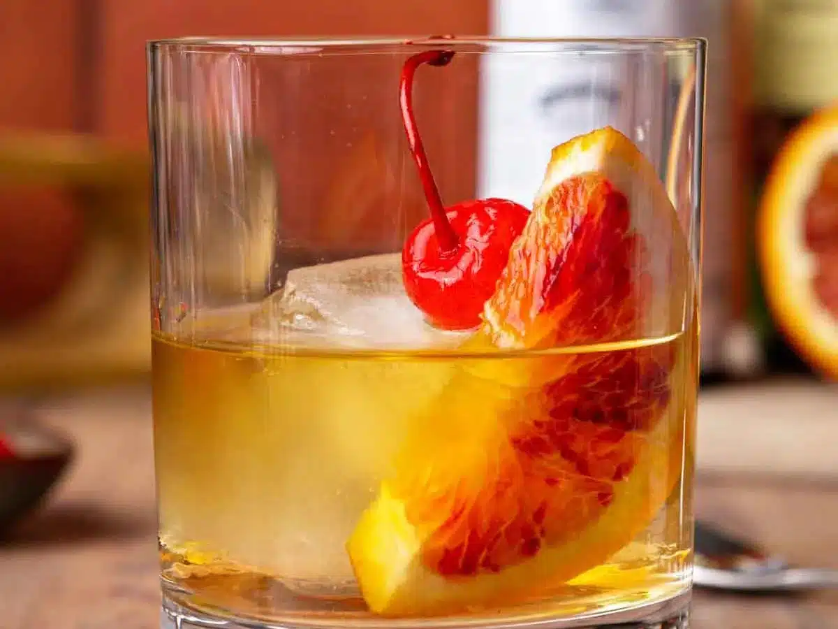 Rocks glass filled with bourbon, orange and cherry garnish.