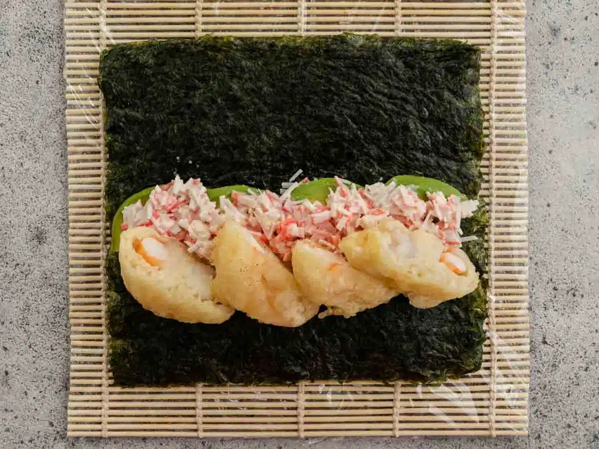 Rice, nori, shrimp and crab on rolling mat.