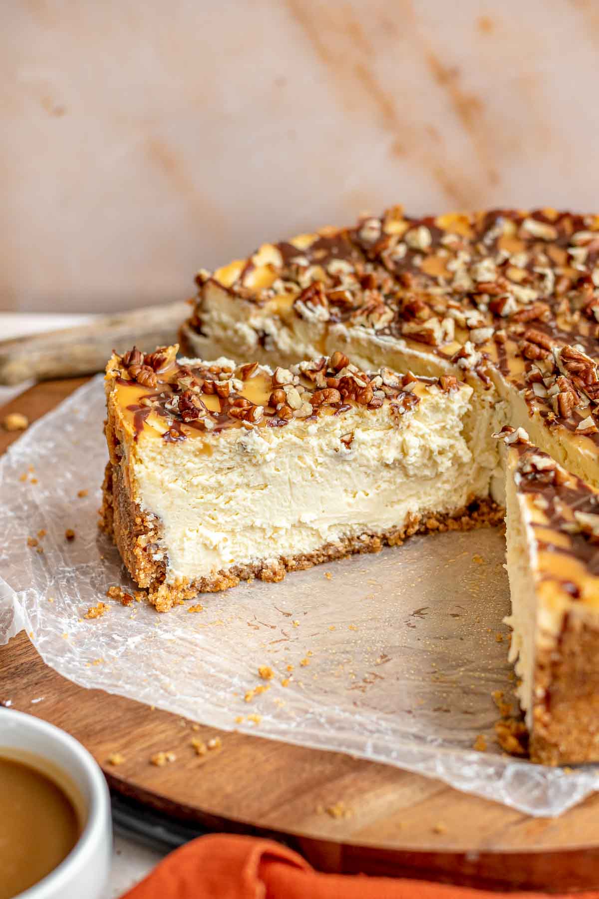 Turtle Cheesecake baked and decorated cheesecake cut in slices on round board, side view