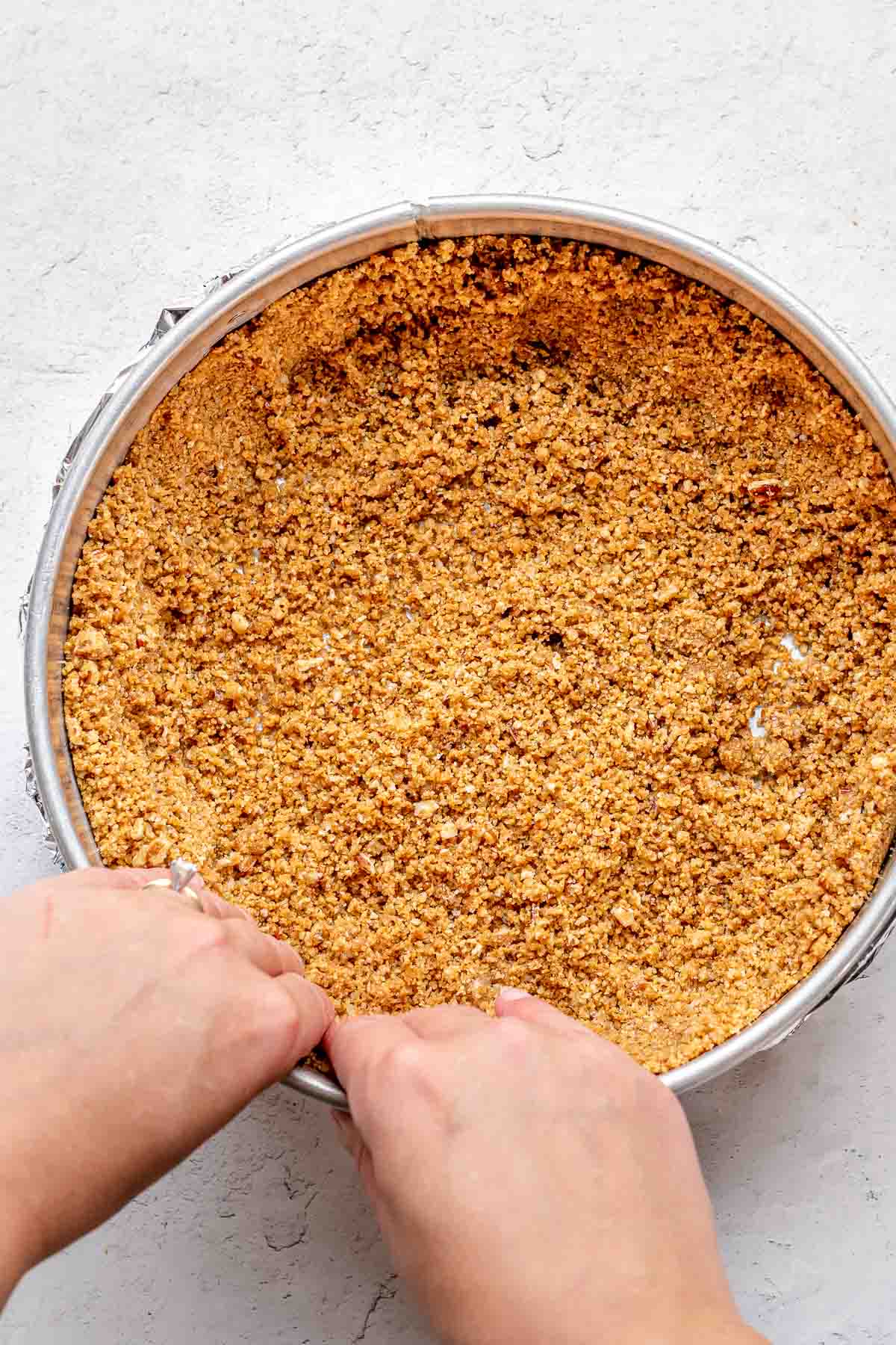 Turtle Cheesecake crust being pressed into pan