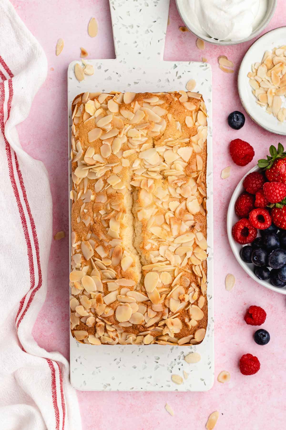 Almond Pound Cake baked on white board, top down view, next to bowl of berries