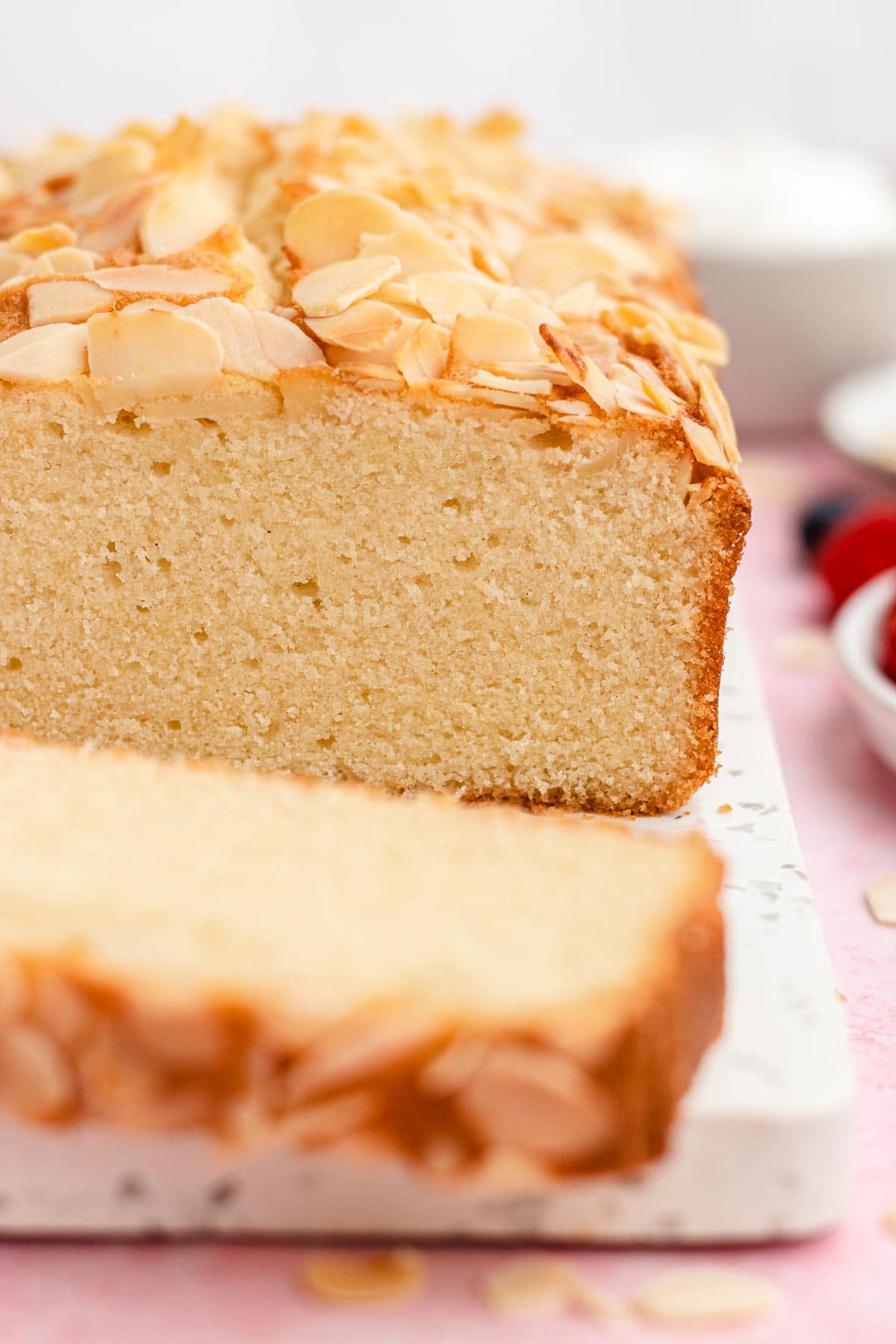 Almond Pound Cake loaf on cutting board with slices cut, front view