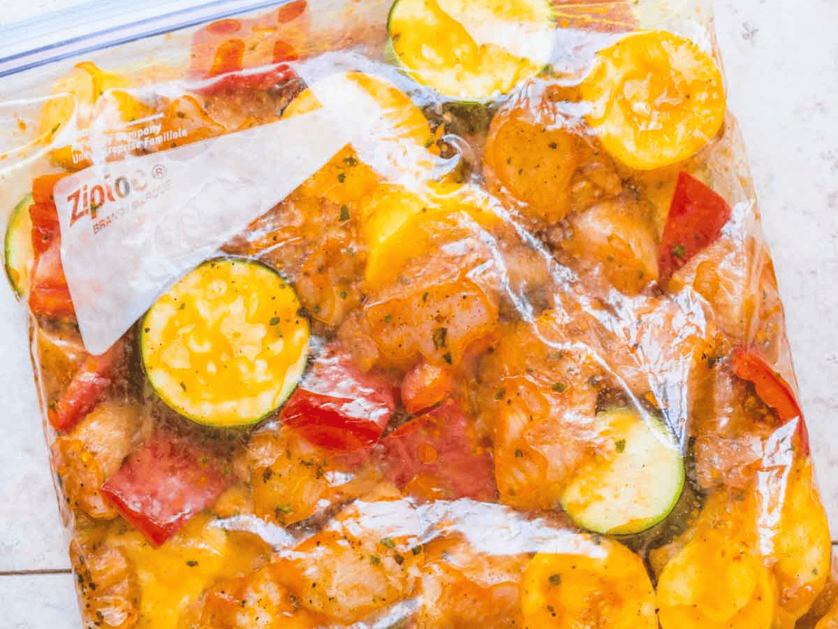 Cubed chicken and vegetables marinating in plastic bag.