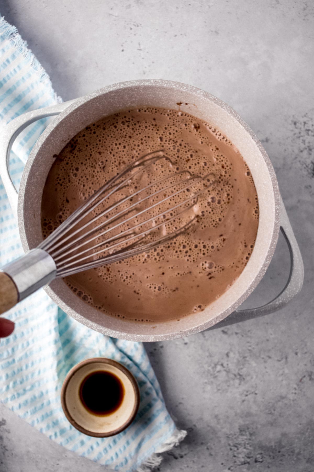 Chocolate Milk whisking chocolate milk in pan with small bowl of vanilla on side