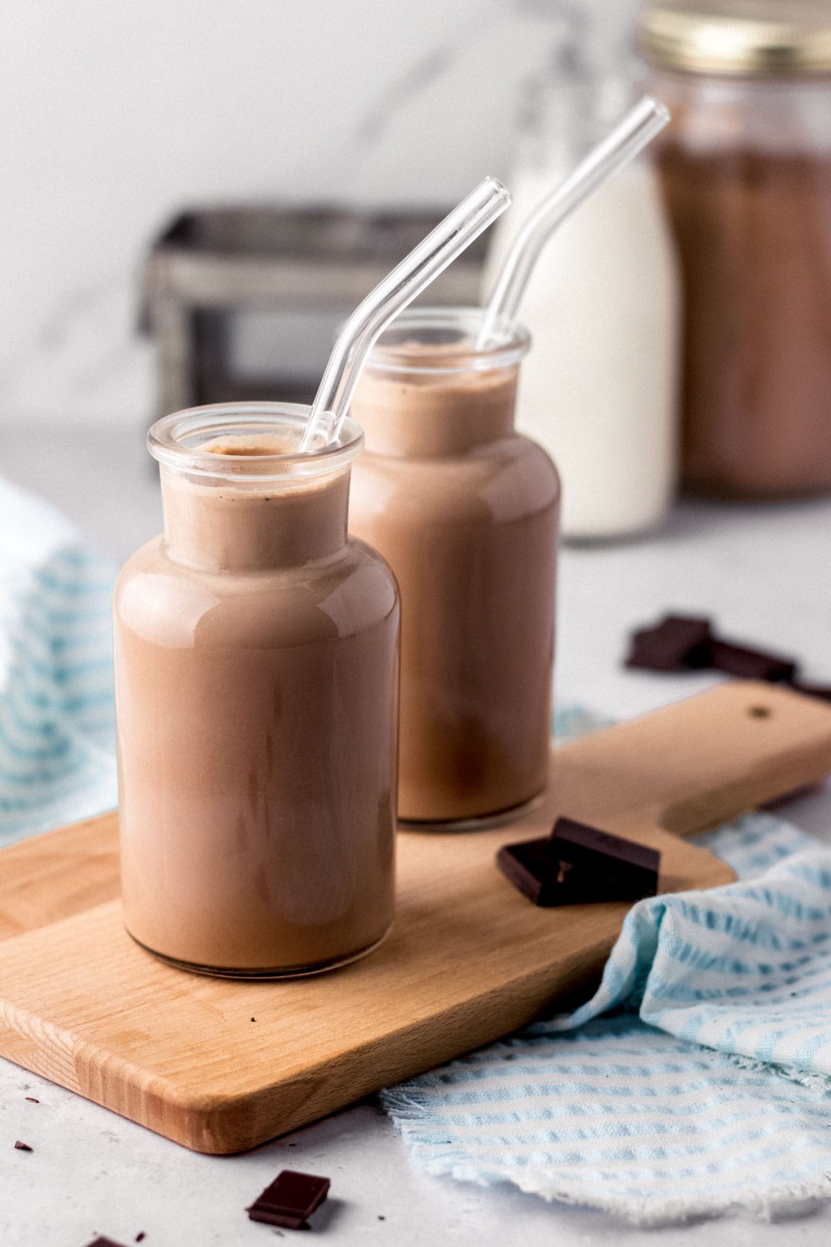 Chocolate Milk two small glass milk jars filled with chocolate milk on cutting board