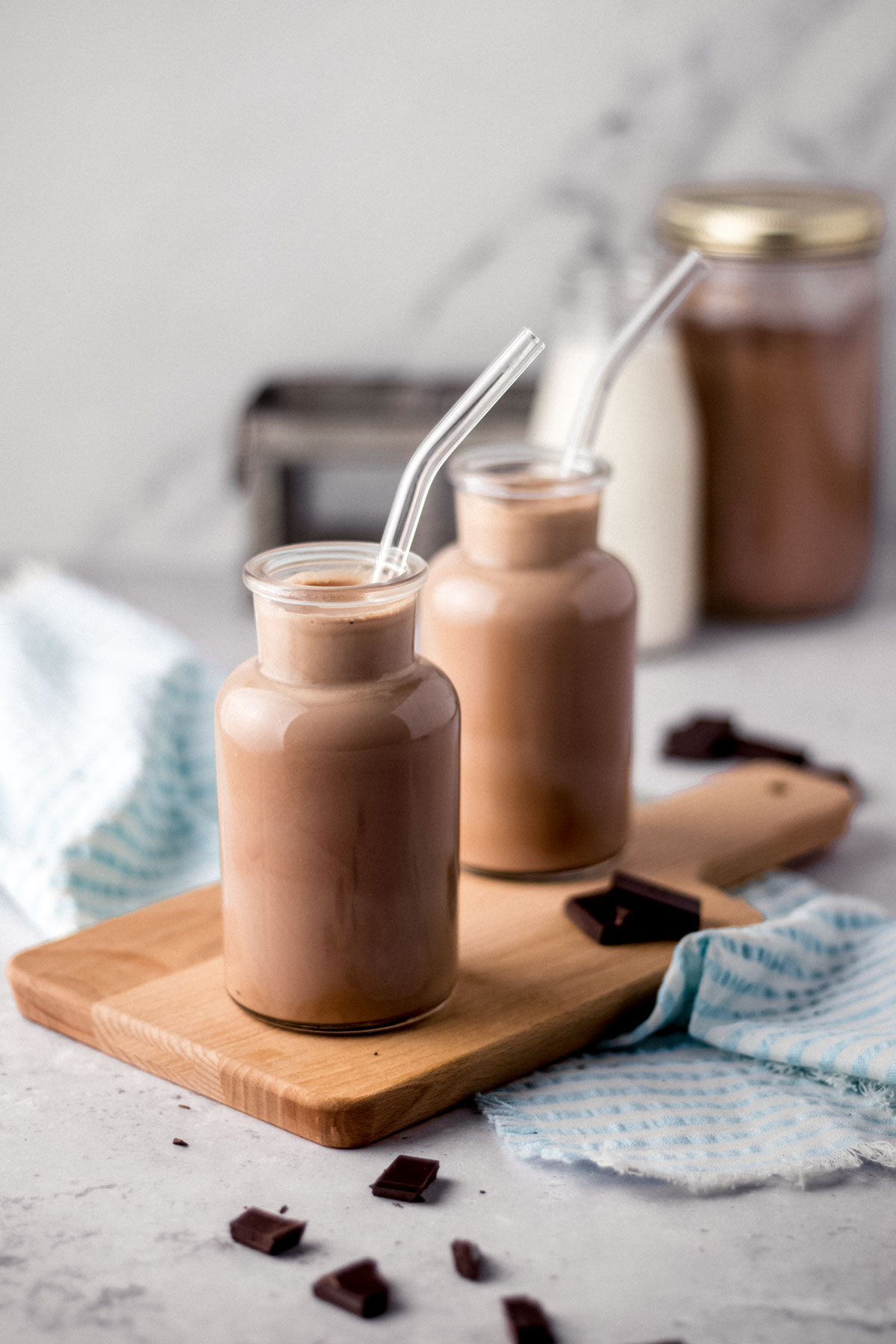 Chocolate Milk two small glass milk jars filled with chocolate milk on cutting board